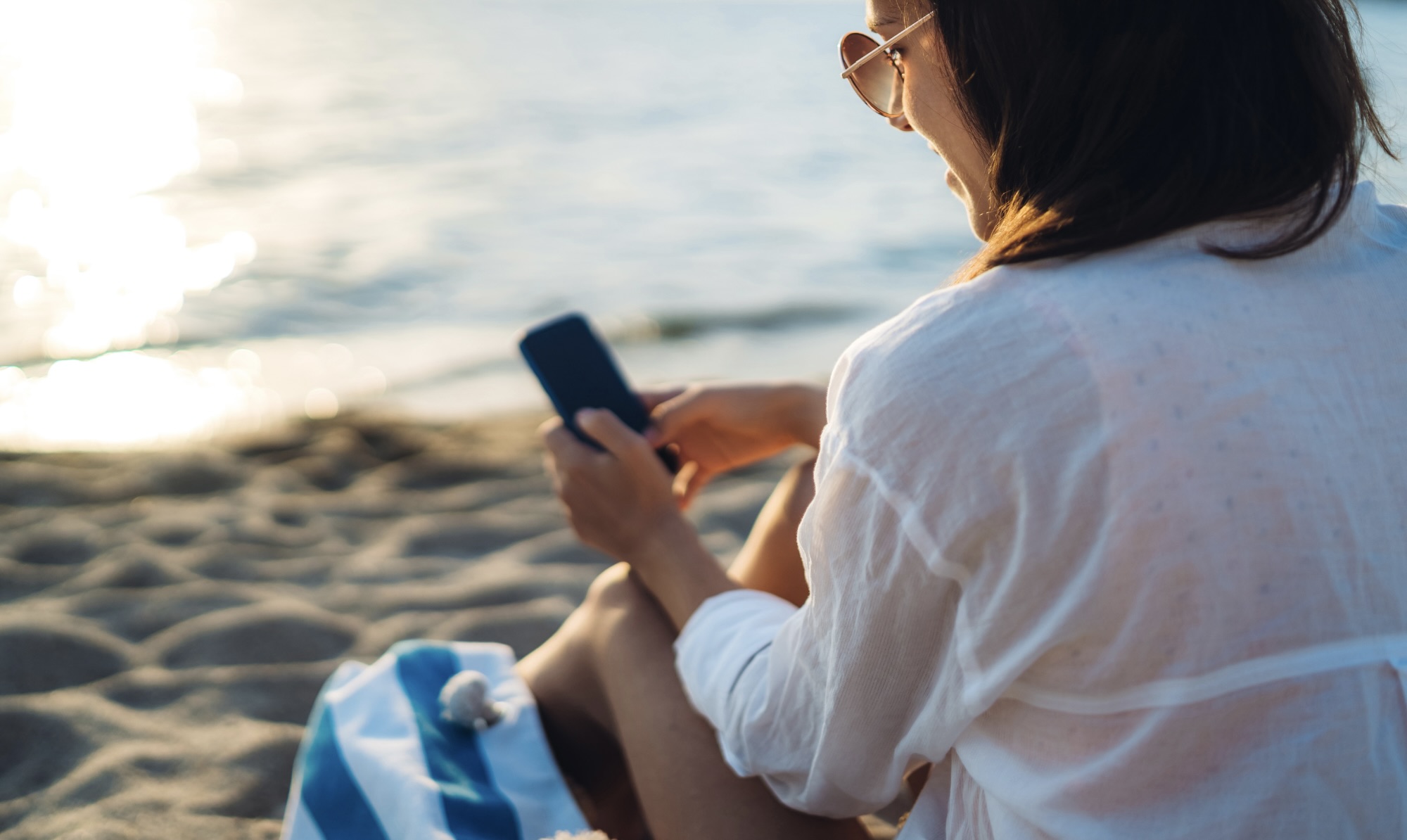 Vrouw op het strand met haar telefoon