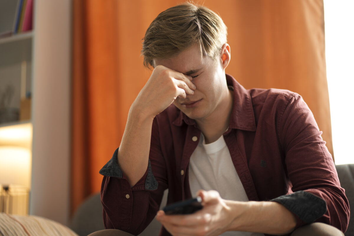 Tienerjongen met telefoon kijkt verdrietig vanwege online haat of digitale uitsluiting