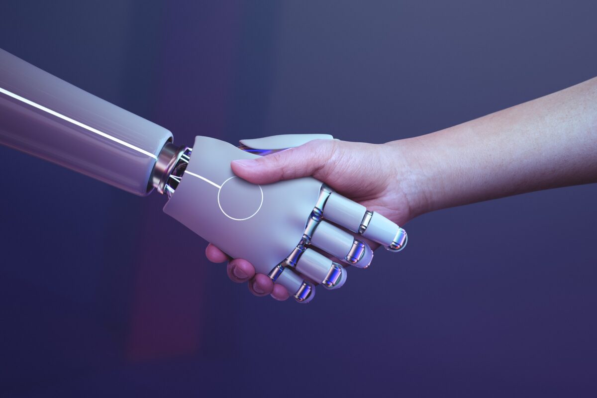 Mens schudt hand met robot – symbolisch beeld van samenwerking tussen jongeren en AI in het onderwijs.