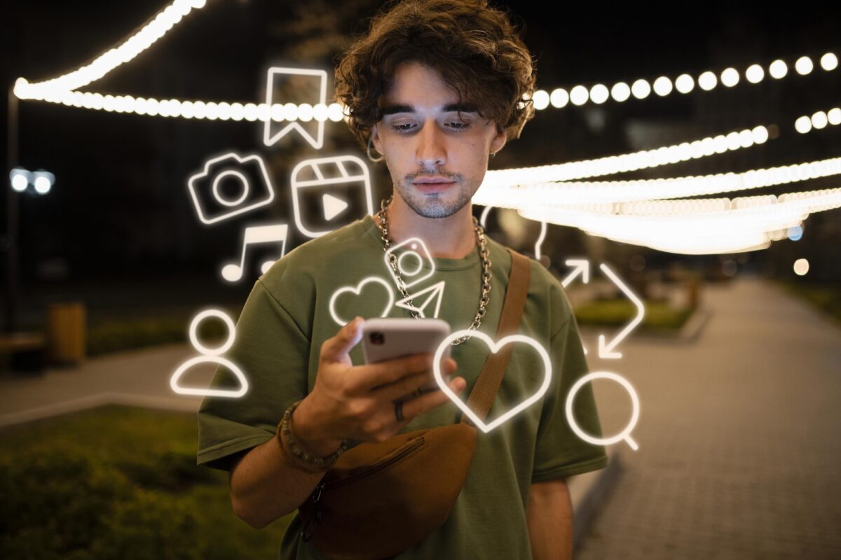 Jonge man bekijkt informatie op zijn telefoon, omringd door sociale media-iconen in de nacht