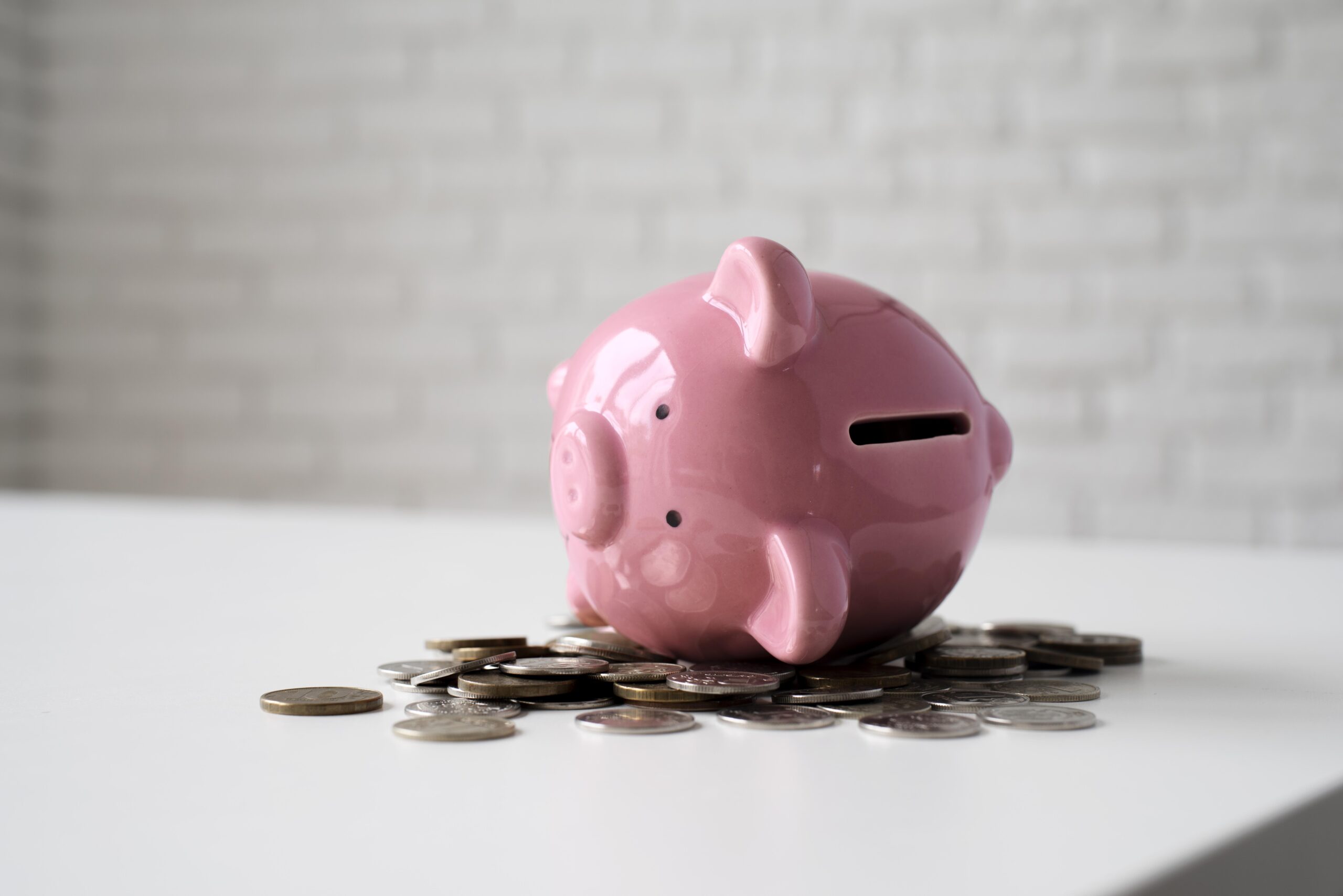 Roze spaarvarken op zijn zij tussen euromunten – symbool voor financiële opvoeding jongeren
