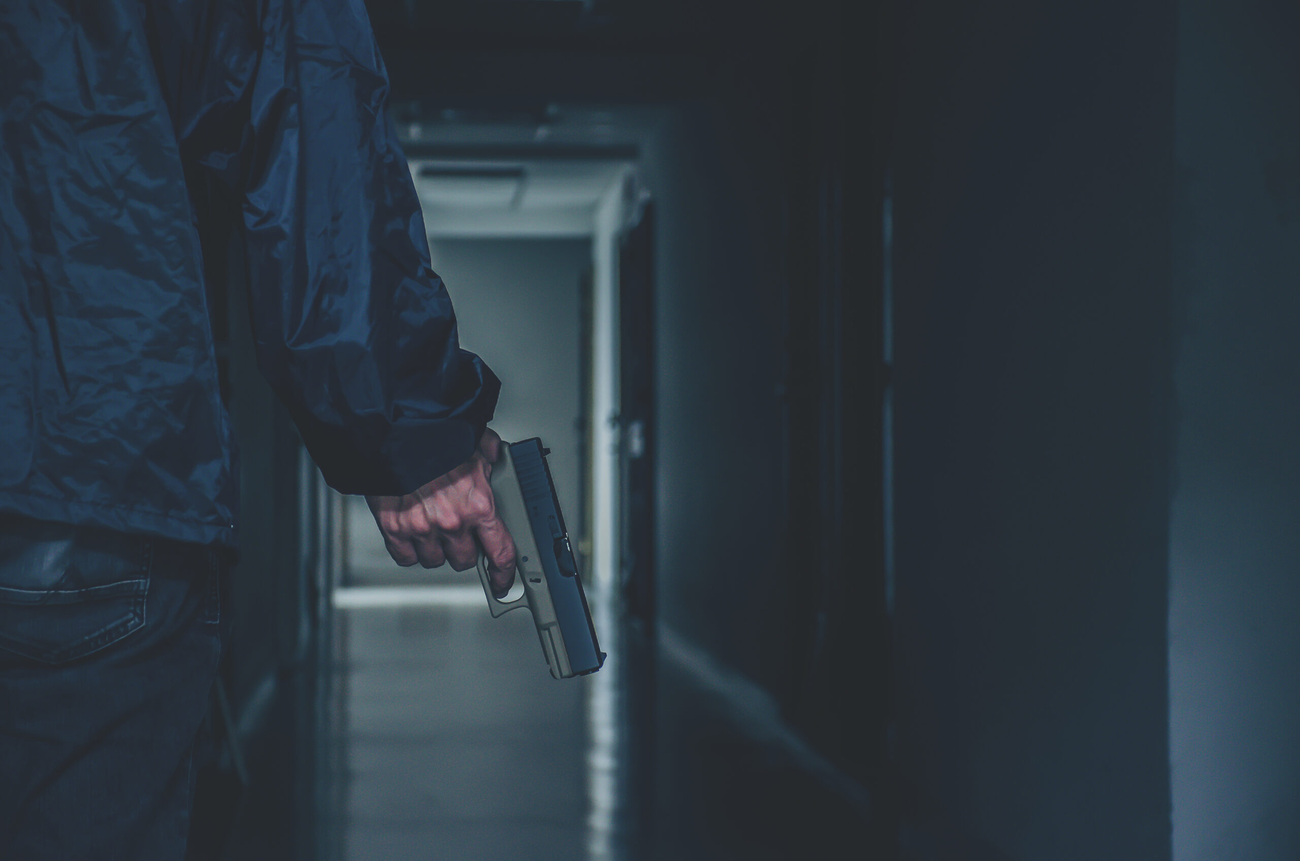 Man met vuurwapen in donkere gang als symbool voor het geweld in de drugscriminaliteit