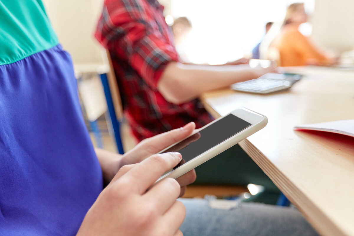 Leerling gebruikt smartphone tijdens de les in een klaslokaal
