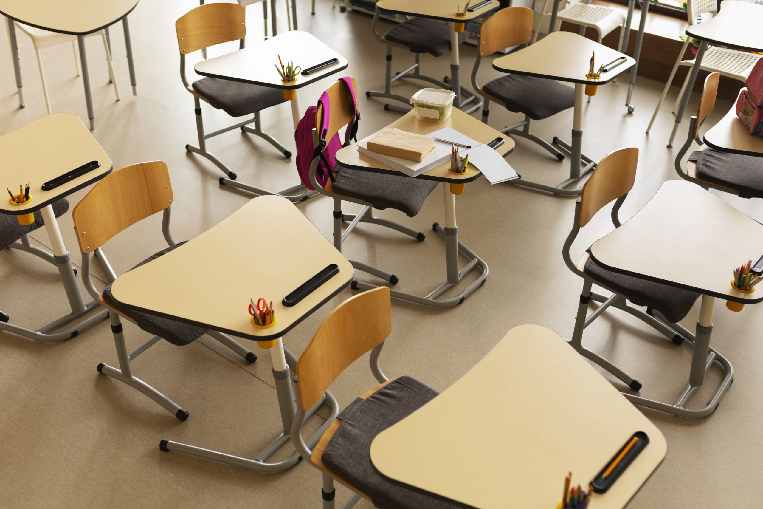 Lege schoolbanken in een klaslokaal met schriften en schoolspullen op tafel