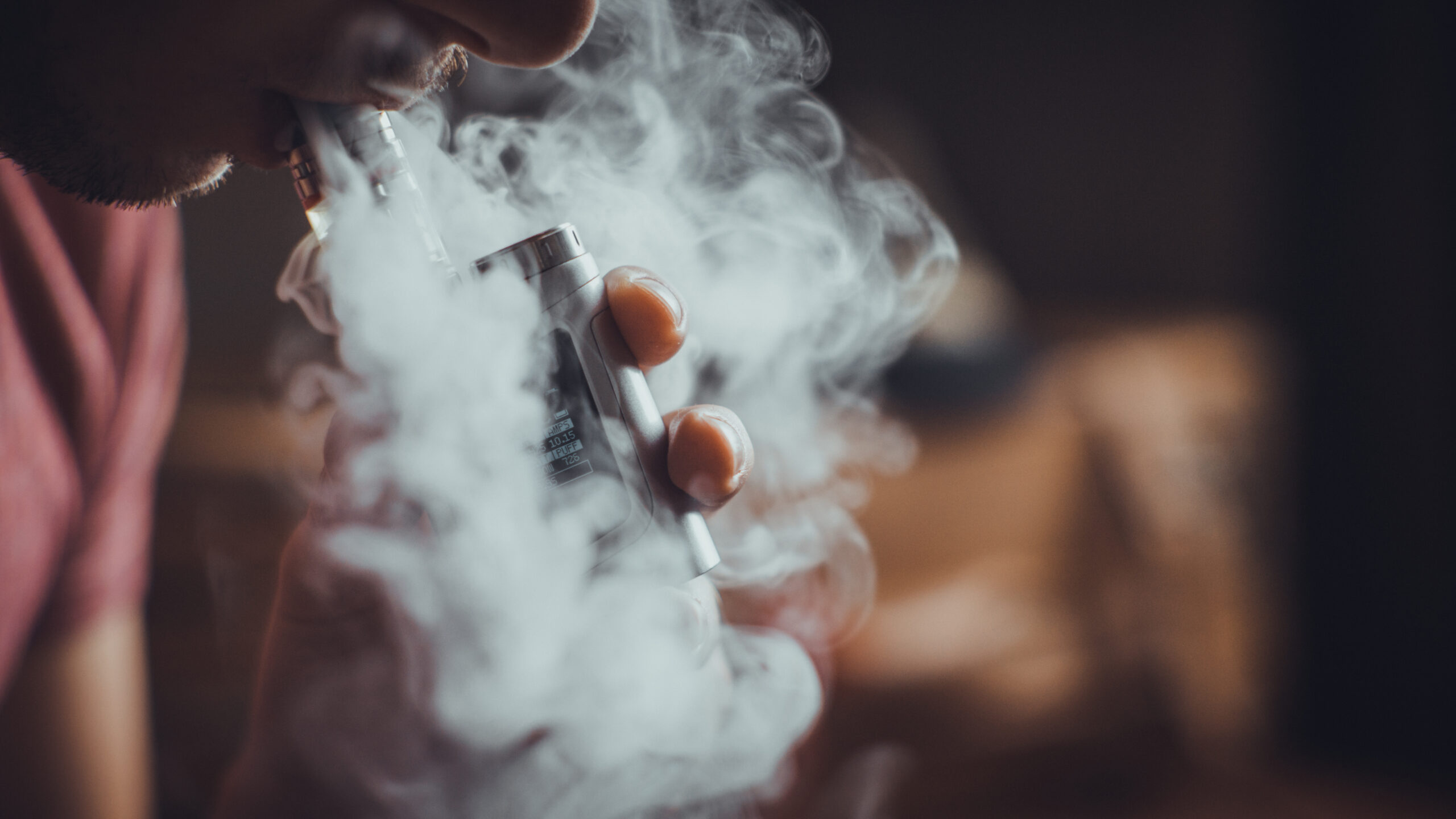 Jongere die een vape gebruikt, met zichtbare dampwolk – illustratief voor de stijgende populariteit van e-sigaretten.