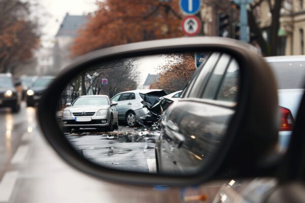Verkeersongeluk tussen twee auto's gezien in de achteruitkijkspiegel – symbool voor de risico’s van verkeersongelukken onder jongeren.