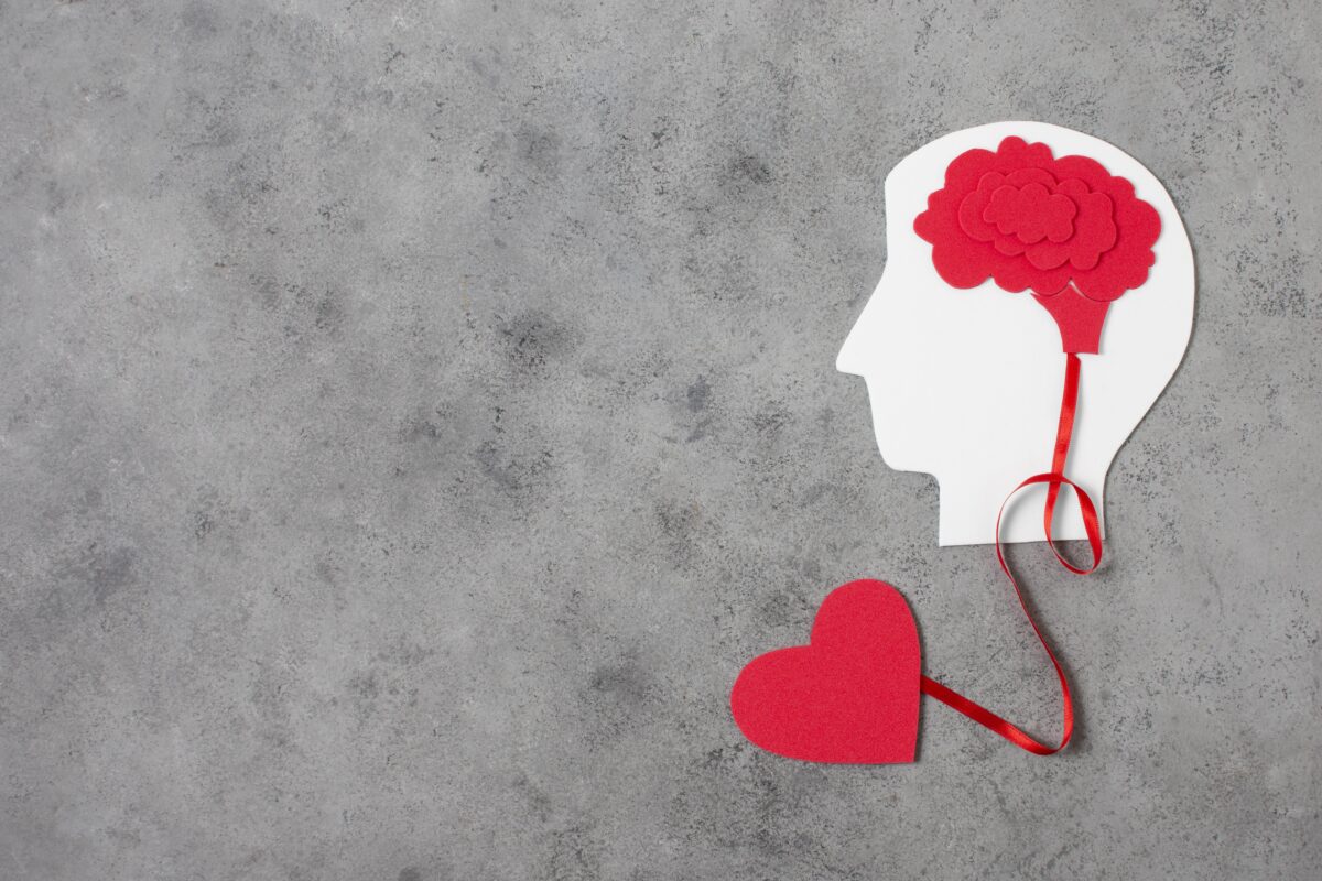Illustratie van een hoofd en hart verbonden met een lint, symbool voor de verbinding tussen mentale gezondheid en emoties.