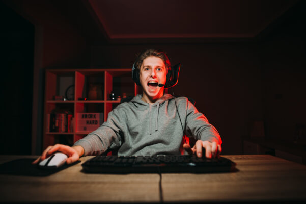 Jonge gamer met headset kijkt enthousiast naar beeldscherm tijdens intens potje gamen