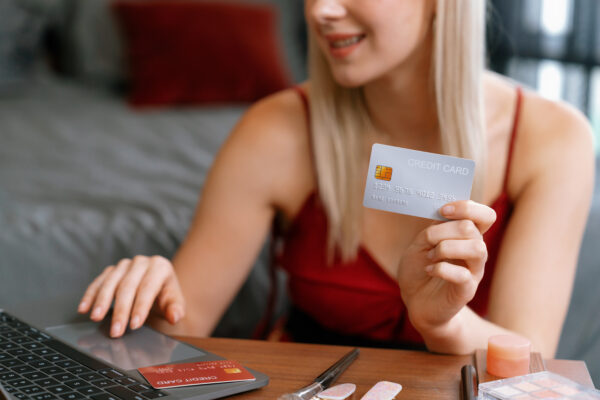 Jonge vrouw gebruikt creditcard bij online aankoop, symbool voor geldzorgen onder jongeren