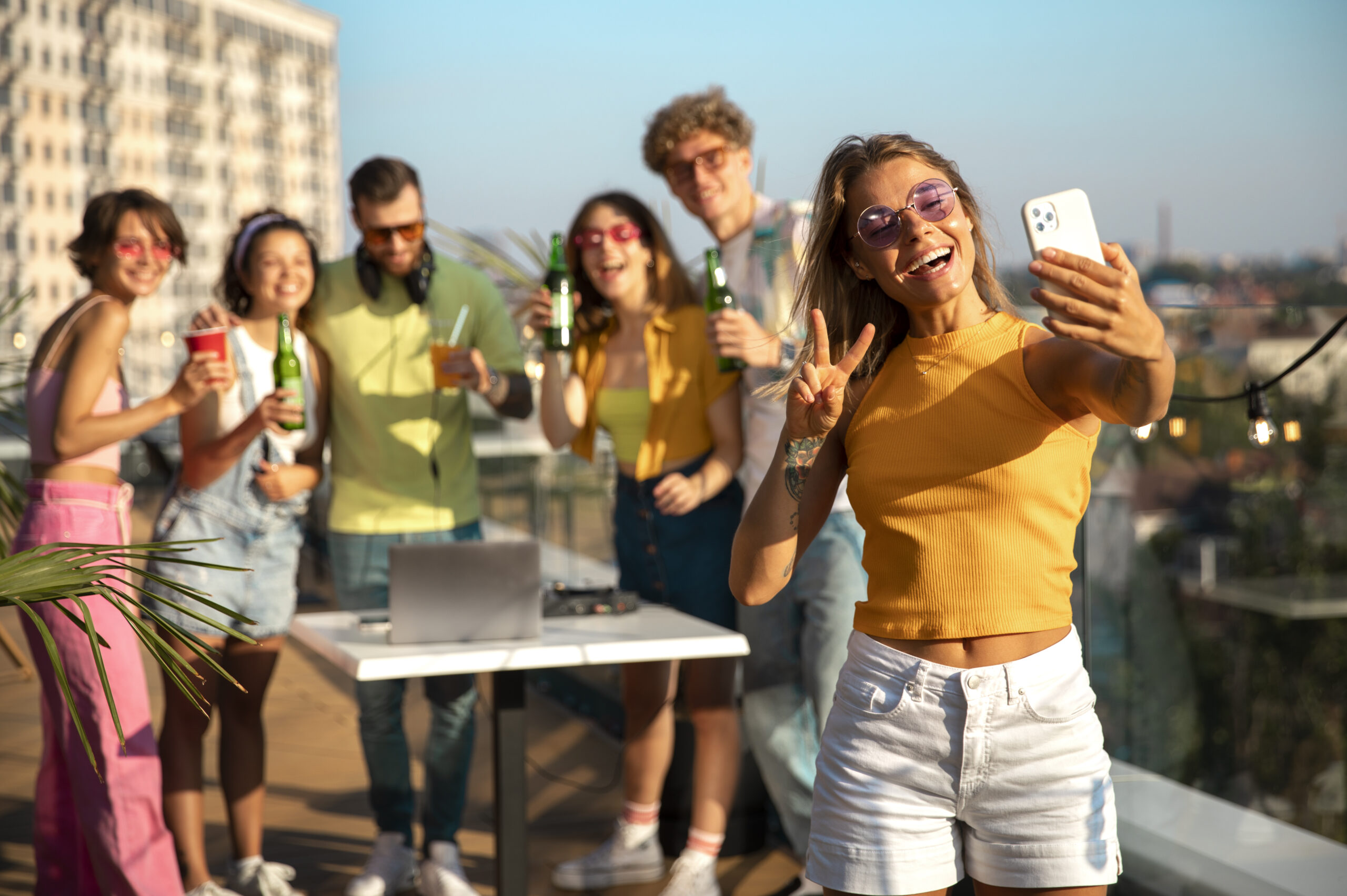 Groep jongeren die feest vieren op een dakterras, met drankjes en een meisje dat een selfie maakt