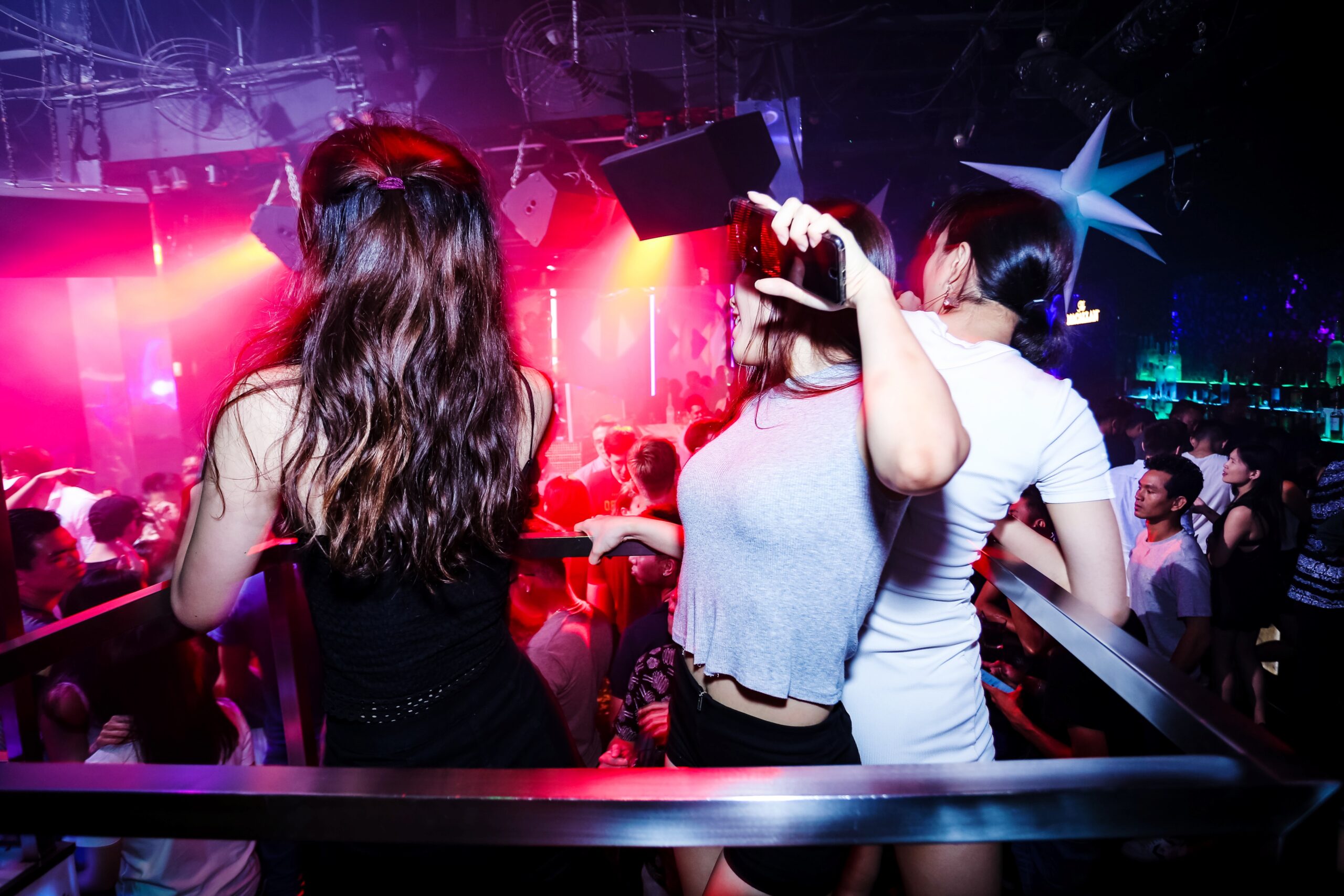 Jongeren dansen in een drukke nachtclub met felle lichten en volle dansvloer.