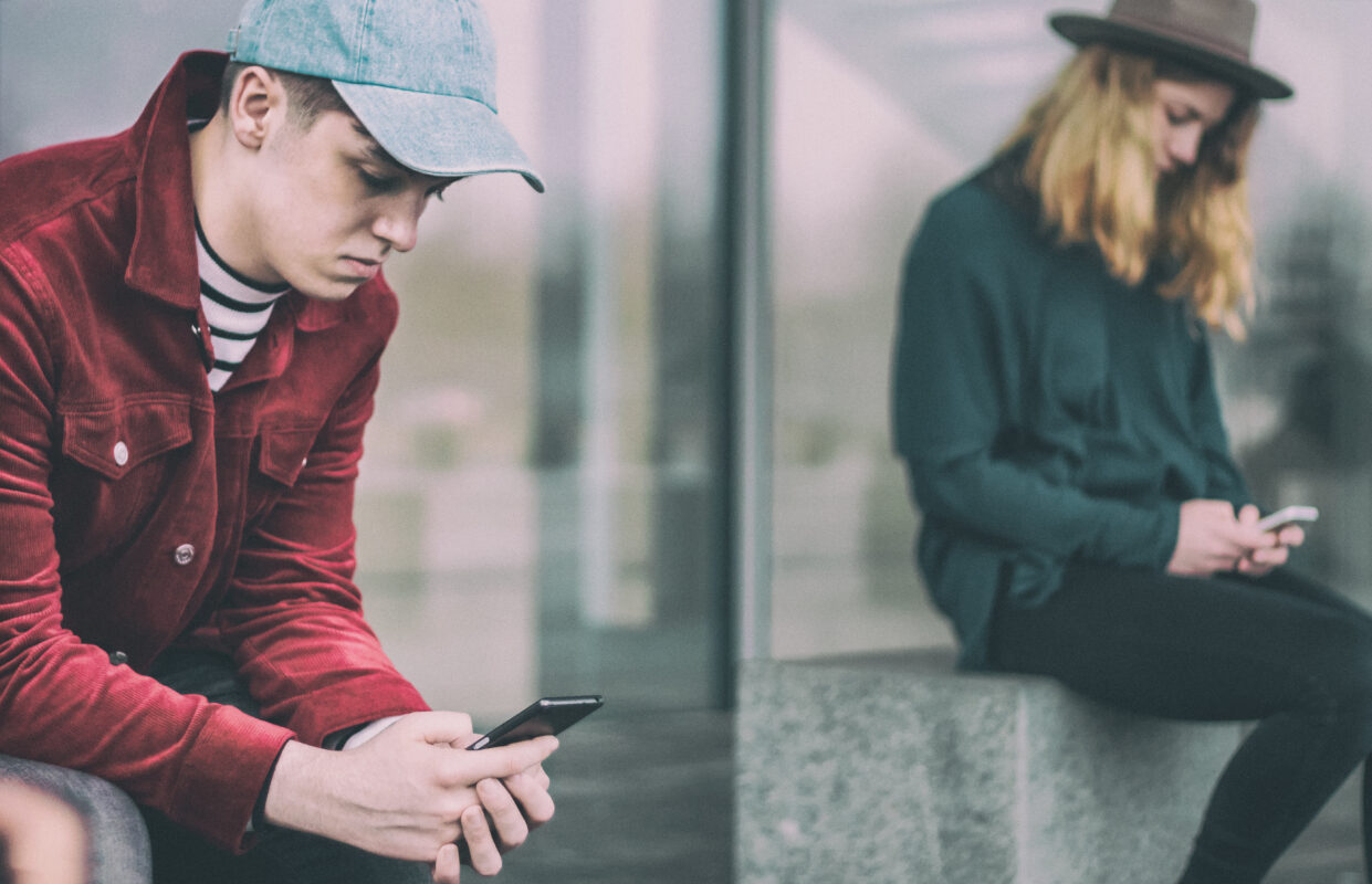 Twee jongeren kijken naar hun smartphone, illustratie van de invloed van sociale media op de mentale gezondheid van jongeren