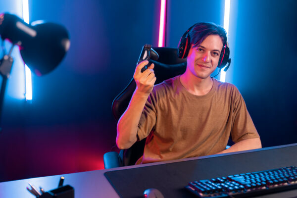ongere met headset en gamecontroller tijdens een livestream achter zijn computer