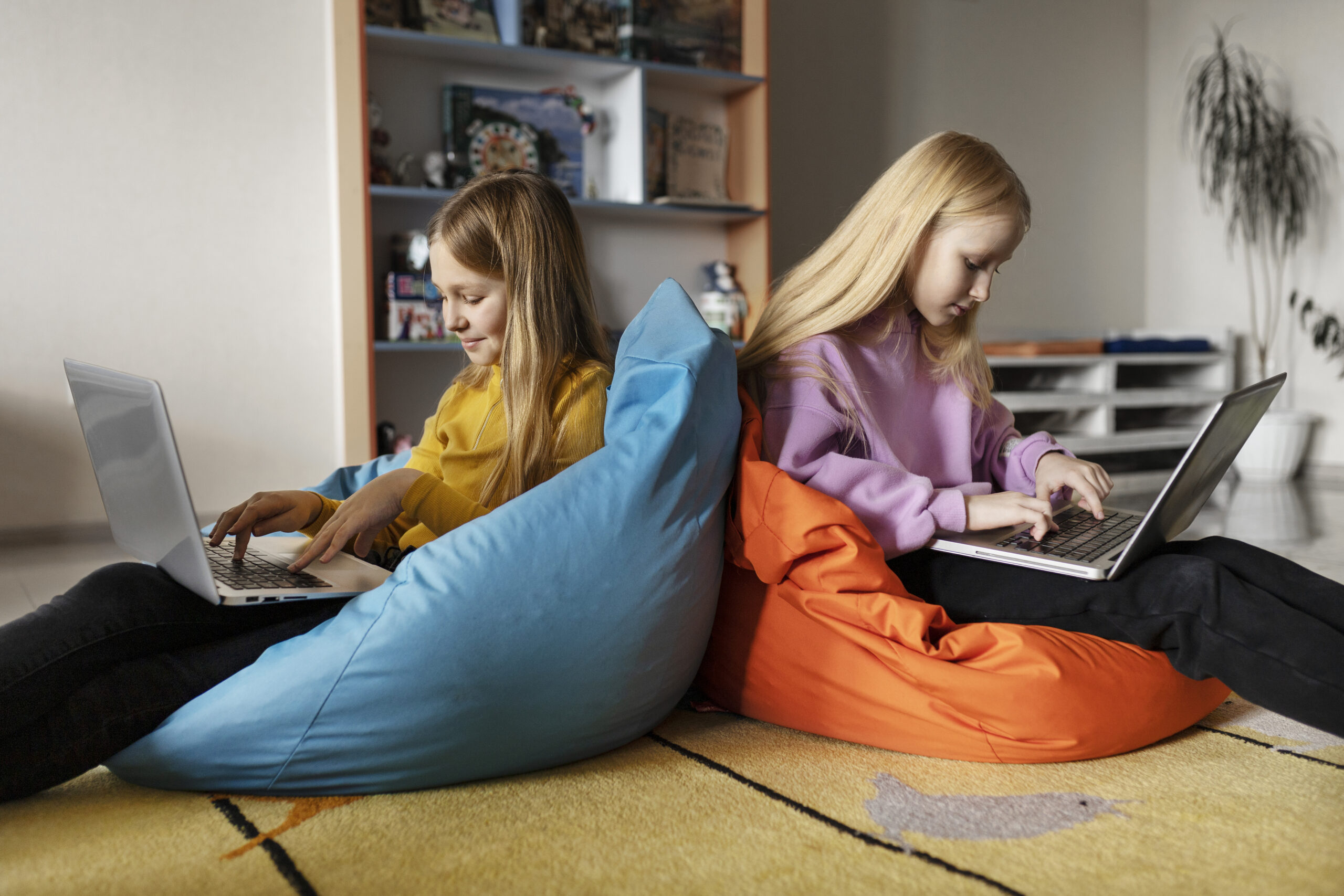 Twee jonge meisjes achter hun laptop online, illustratie bij risico’s van chatplatforms zoals Thundr.