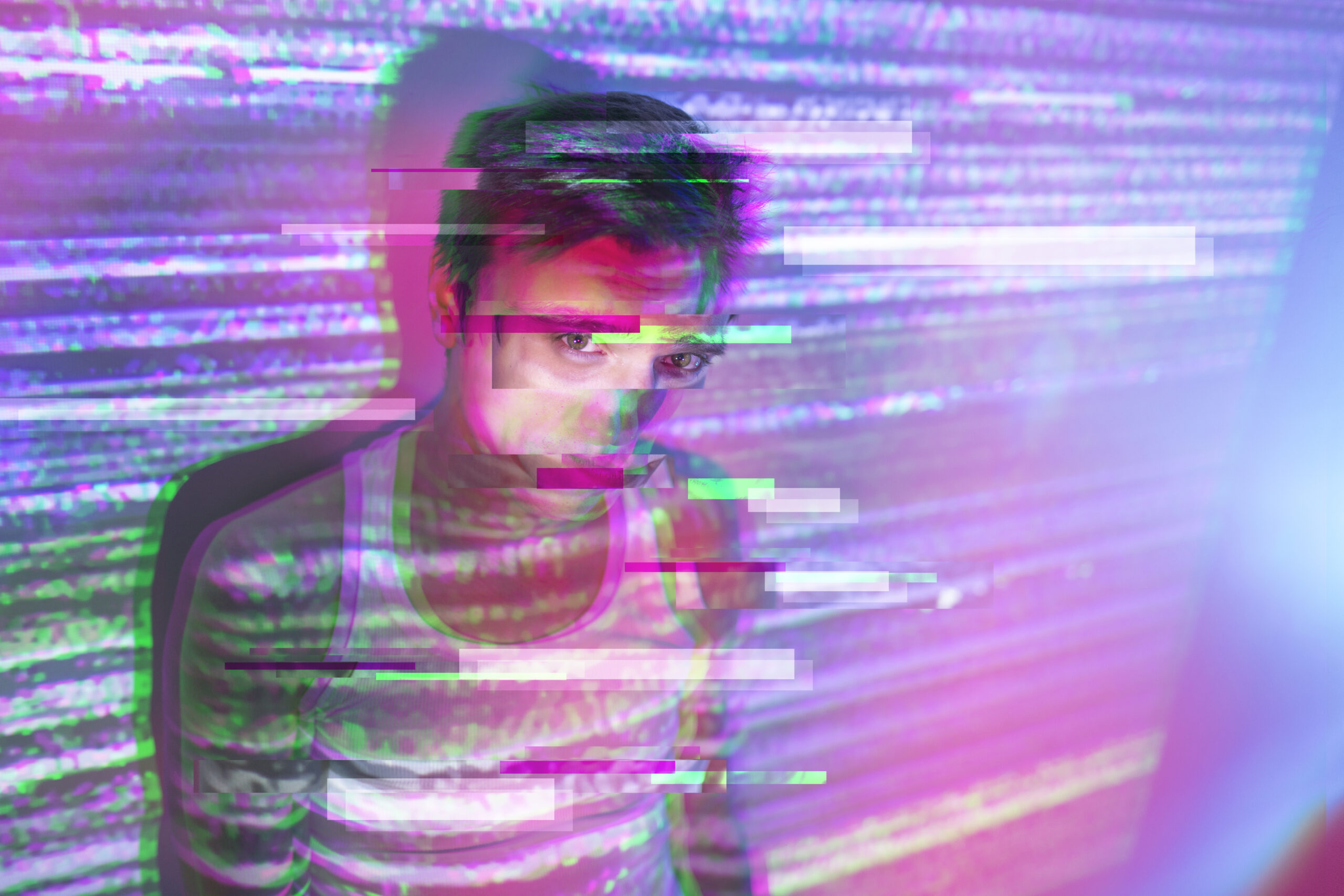 Jongere kijkt in felgekleurde digitale lichtprojectie met glitch-effect, symbool voor verdwalen in online prikkels en goonen.