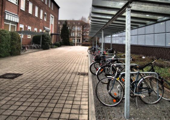 fietsen geparkeerd bij een schoolplein met bakstenen gebouw en metalen overkapping