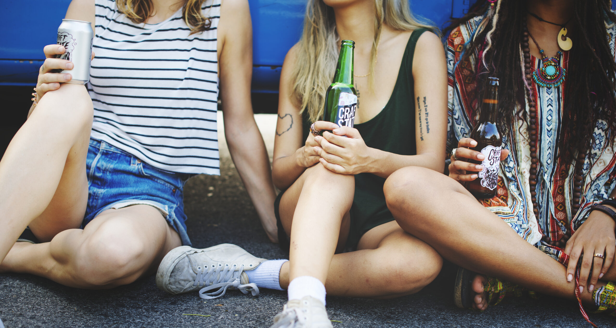 Jongeren zitten op de grond met flesjes alcohol tijdens een bijeenkomst buitenshuis.