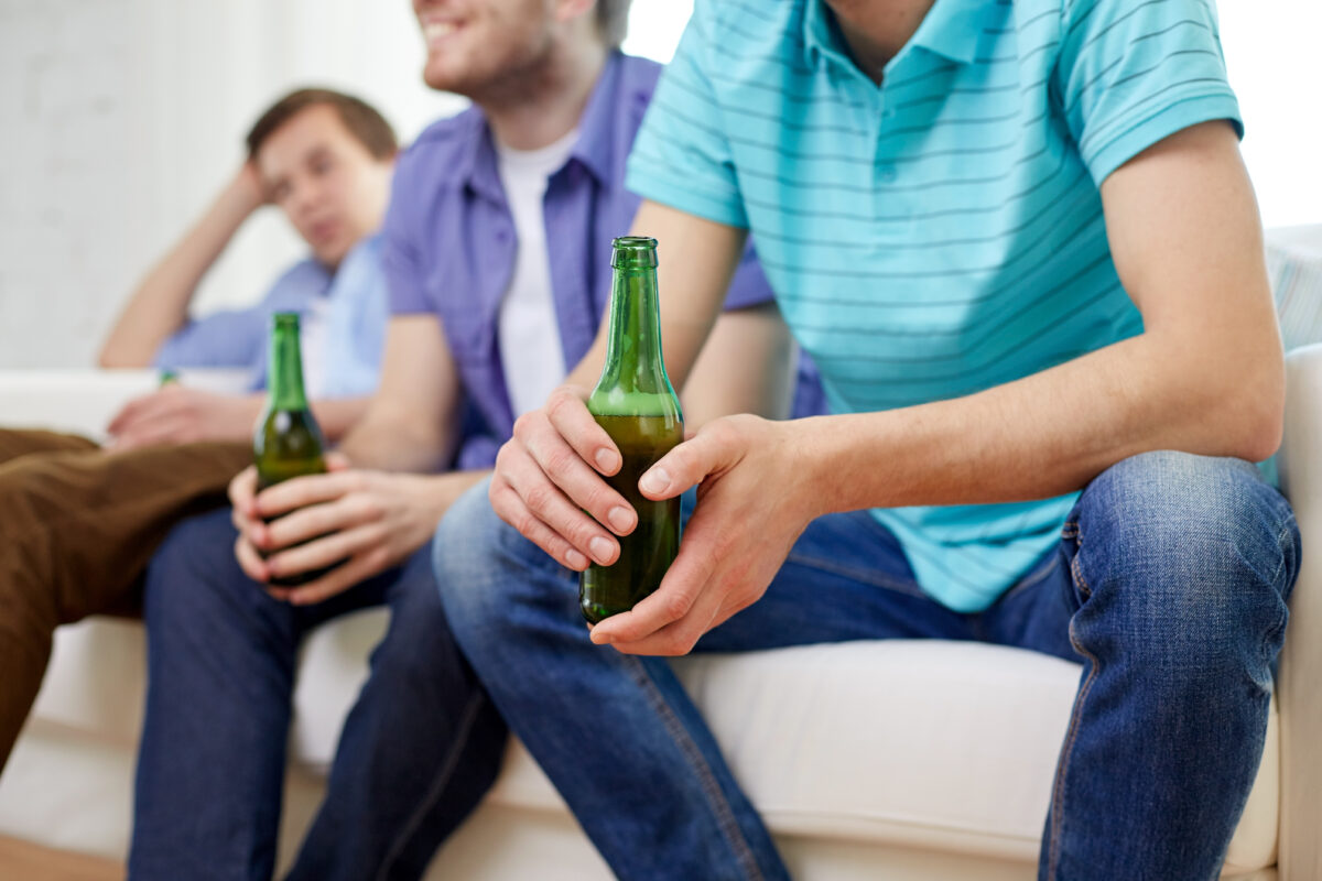 Jongeren drinken bier tijdens een sociale bijeenkomst thuis