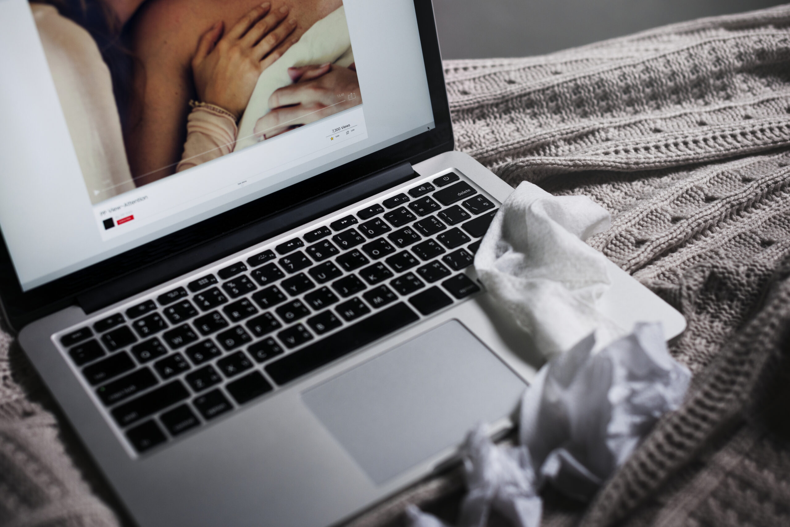 Laptop op bed met op het scherm expliciete online content, symbool voor online misbruik en digitale grenzen bij jongeren