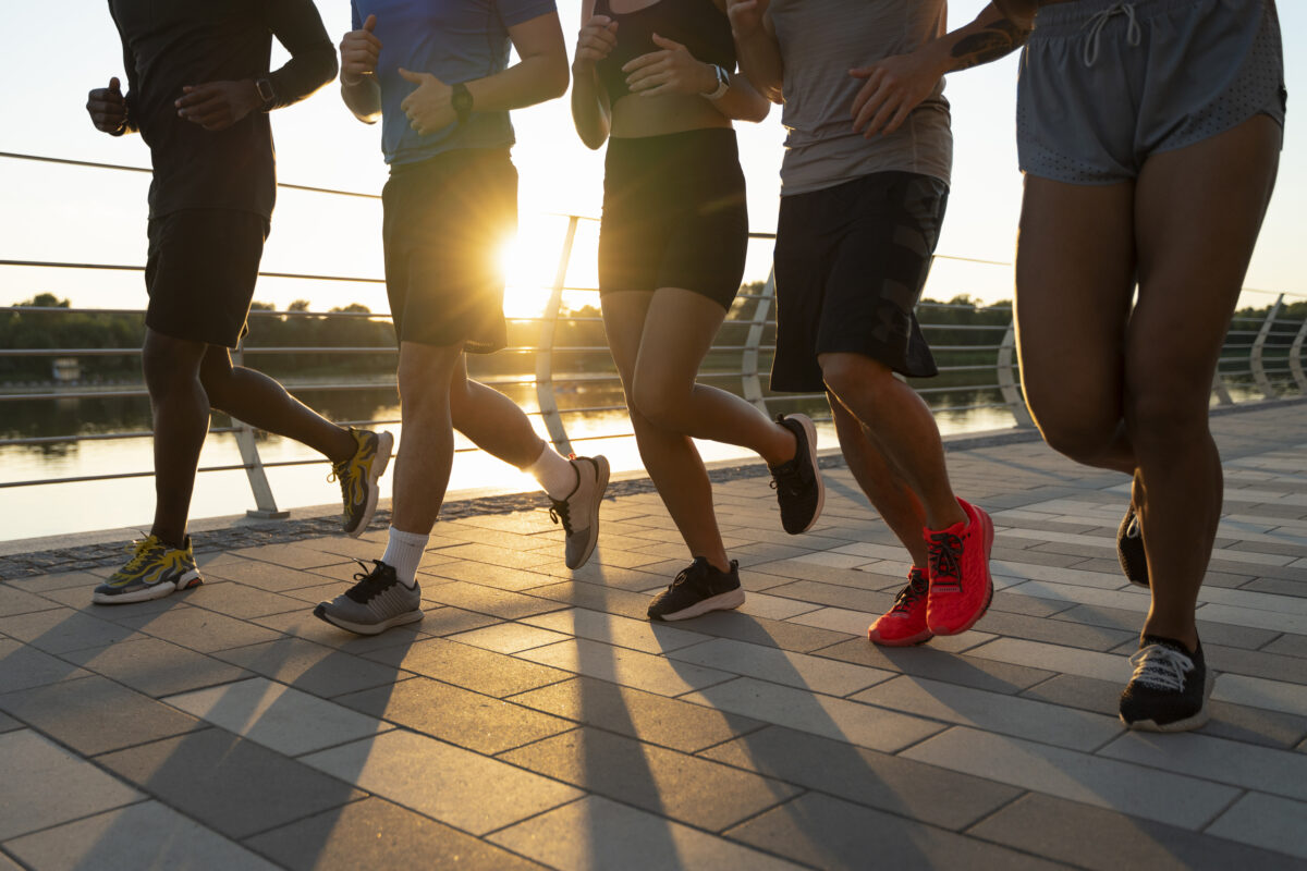 Jongeren die samen hardlopen langs het water tijdens zonsondergang.