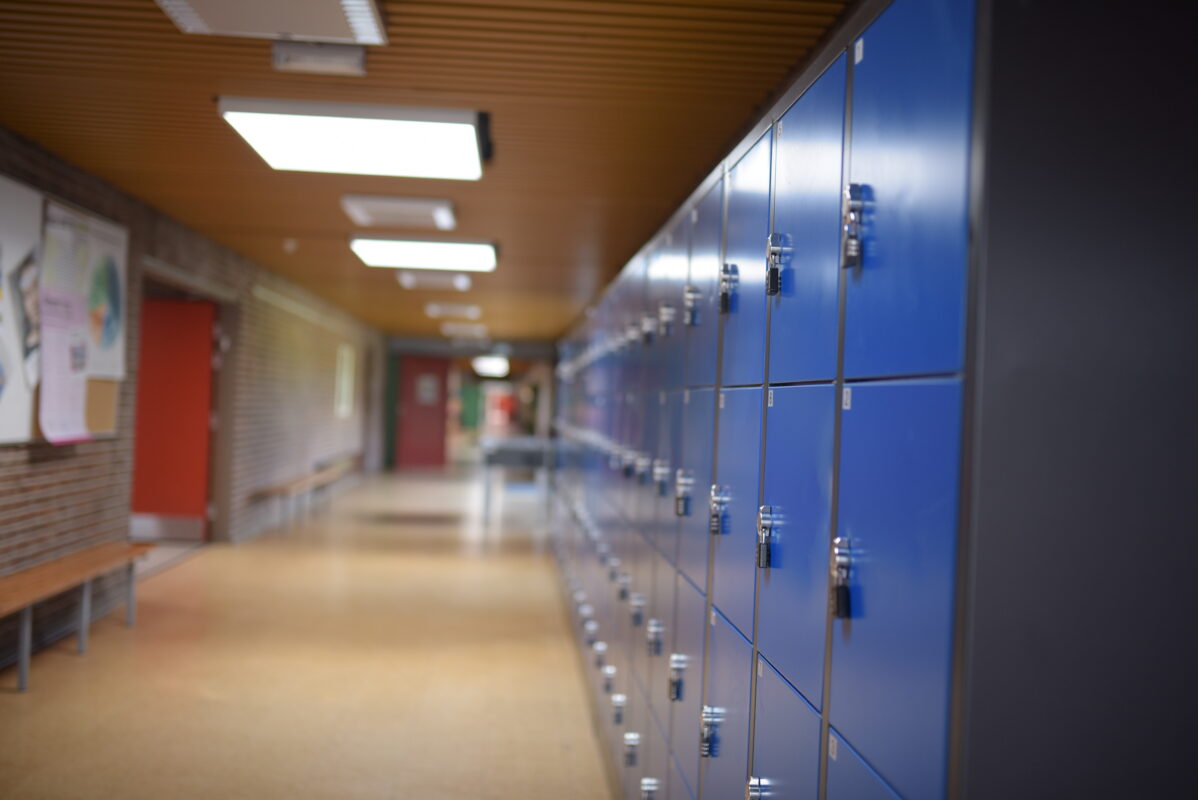 Lege schoolgang met blauwe kluisjes, symbool voor jongeren die onzichtbaar worstelen met mentale problemen.