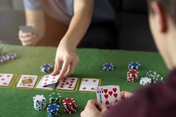 Jongeren spelen poker aan tafel met speelkaarten en fiches, focus op kaarten en stapels chips.