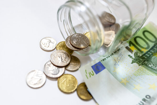 Glazen pot met euromunten en briefgeld op witte achtergrond als symbool voor schulden en uitgaven van jongeren