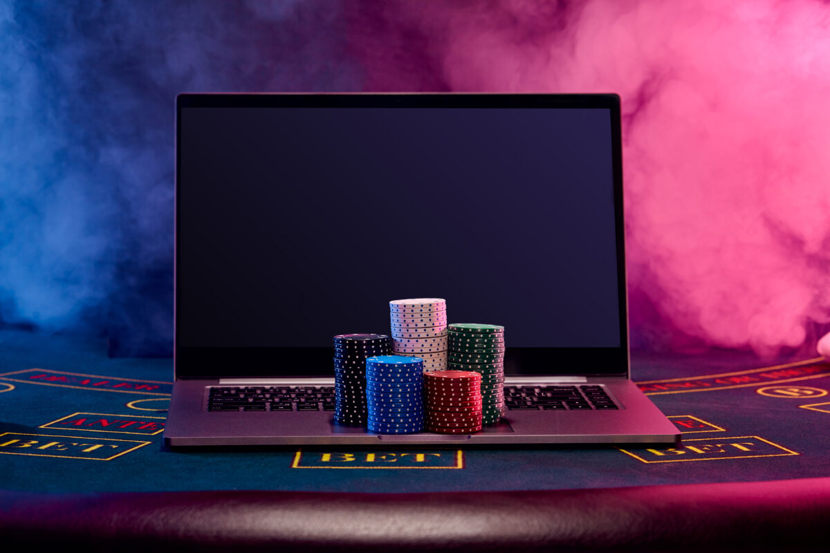 Laptop met pokerchips op een speeltafel, symbool voor online gokken en illegale goksites.