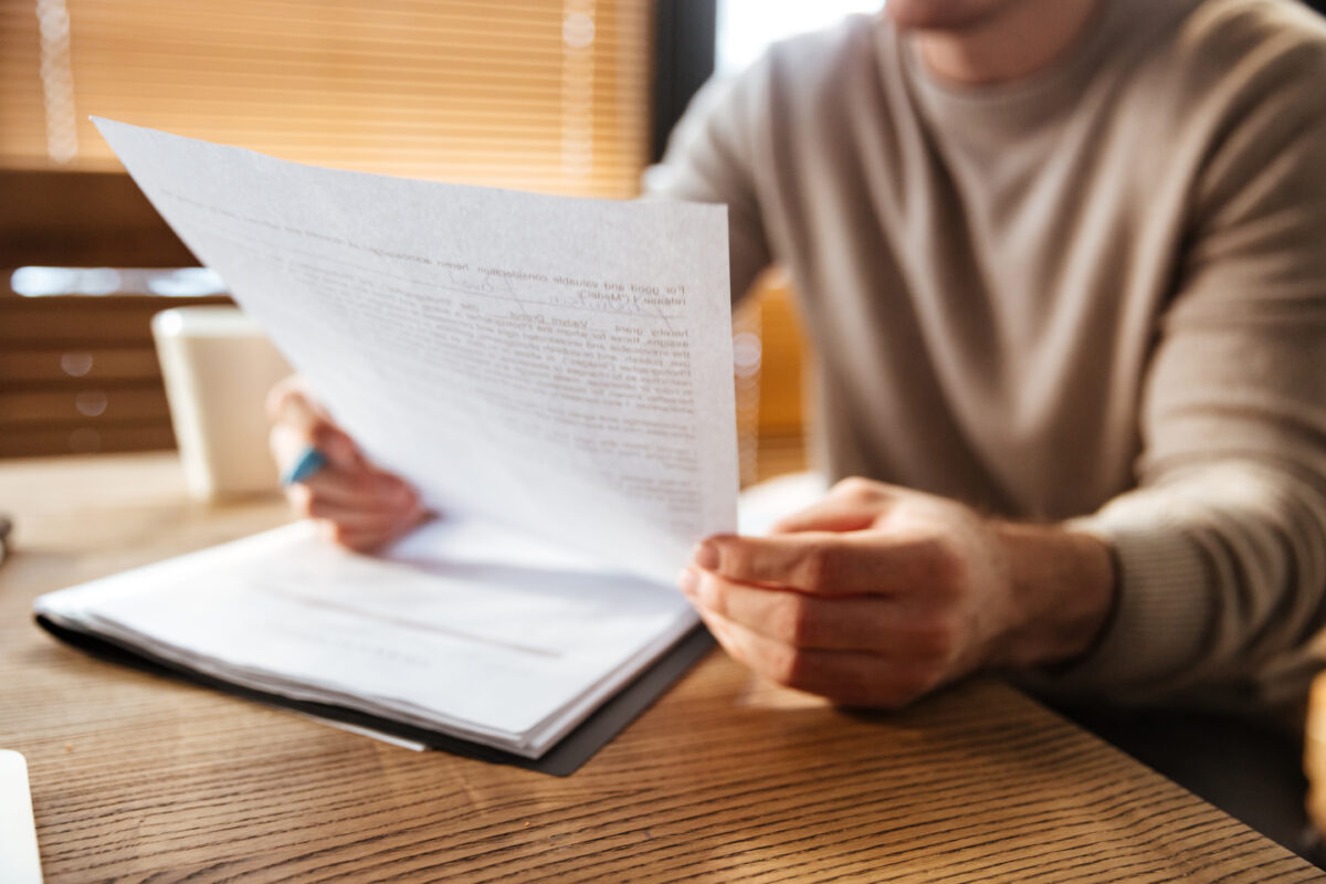 Jongere zit aan een tafel en leest aandachtig een document, wat symbool staat voor zorgen en verantwoordelijkheden waar jongeren mee te maken kunnen krijgen.
