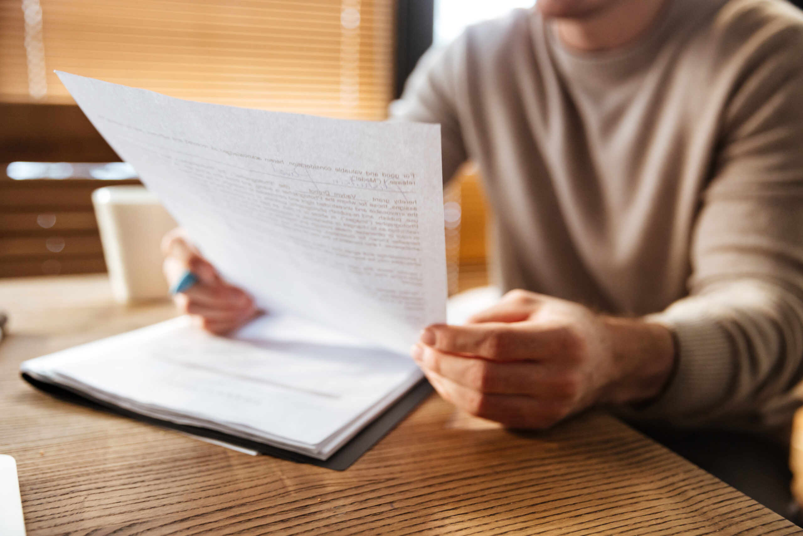 Jongere zit aan een tafel en leest aandachtig een document, wat symbool staat voor zorgen en verantwoordelijkheden waar jongeren mee te maken kunnen krijgen.