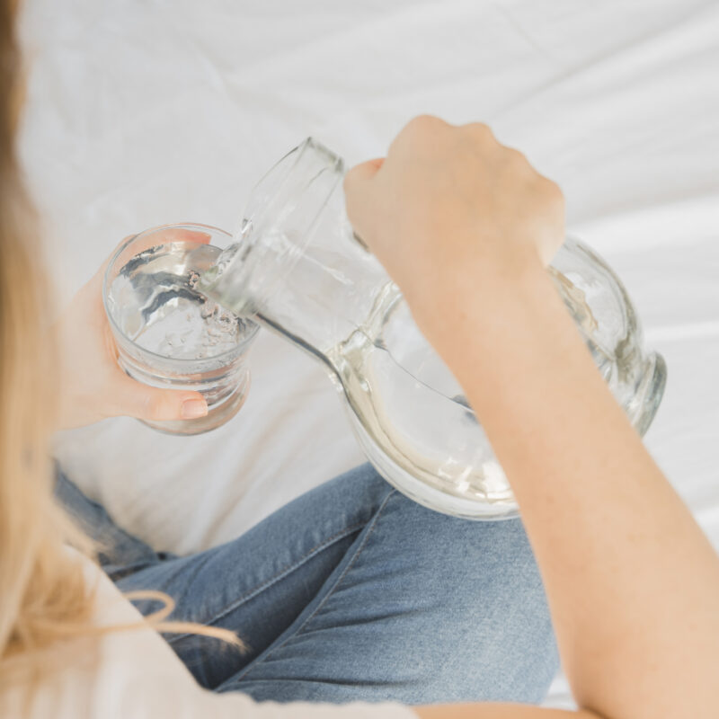 Jongere schenkt water in een glas, passend bij het thema watervergiftiging en bewust omgaan met water drinken