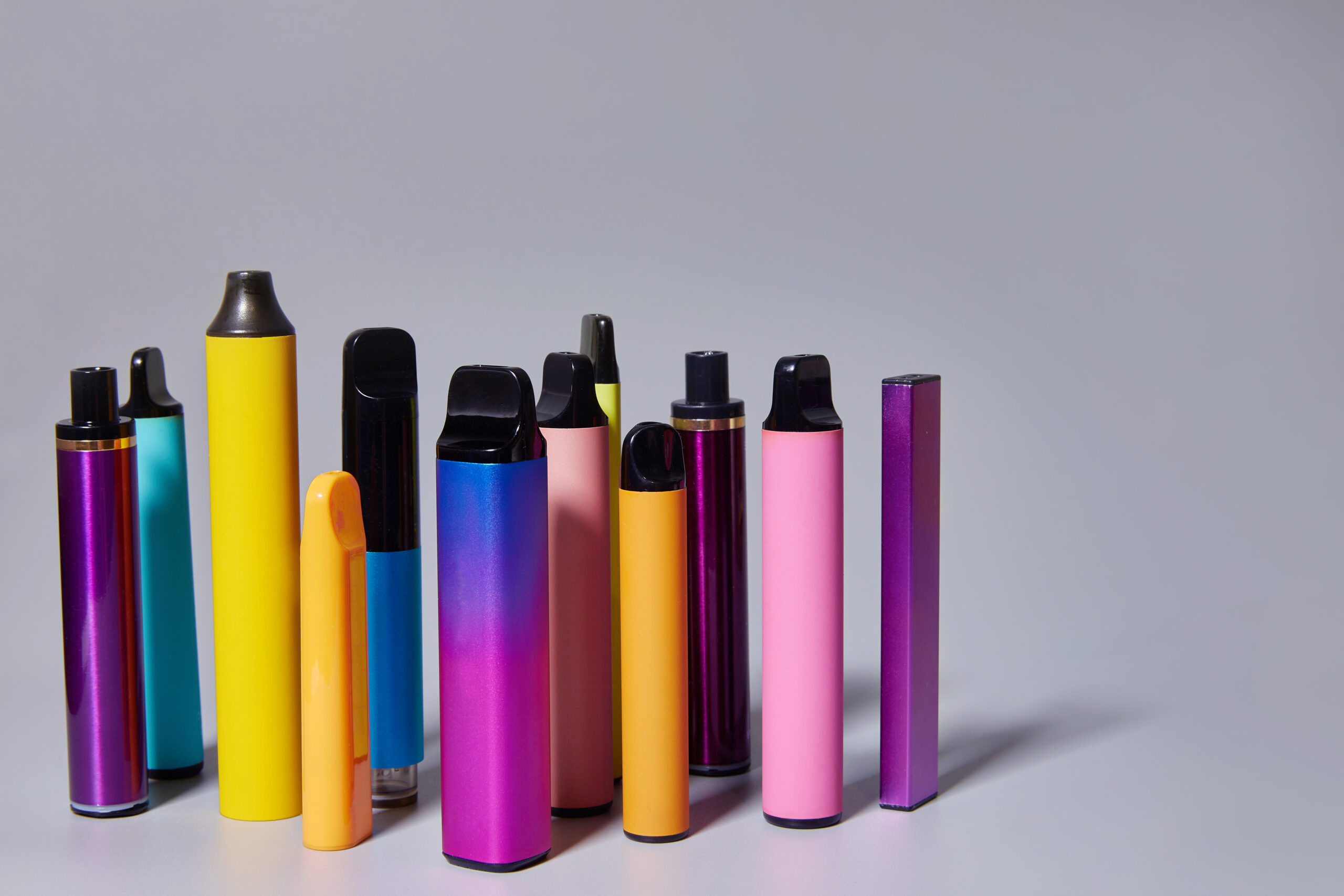 Verschillende kleurrijke vapes naast elkaar op een neutrale achtergrond