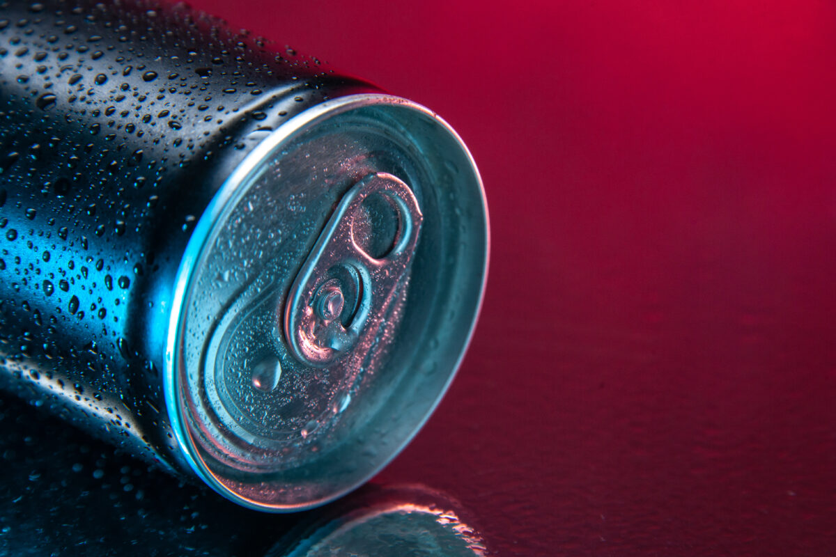 Blikje energiedrank met condensdruppels op een roze en donkere achtergrond