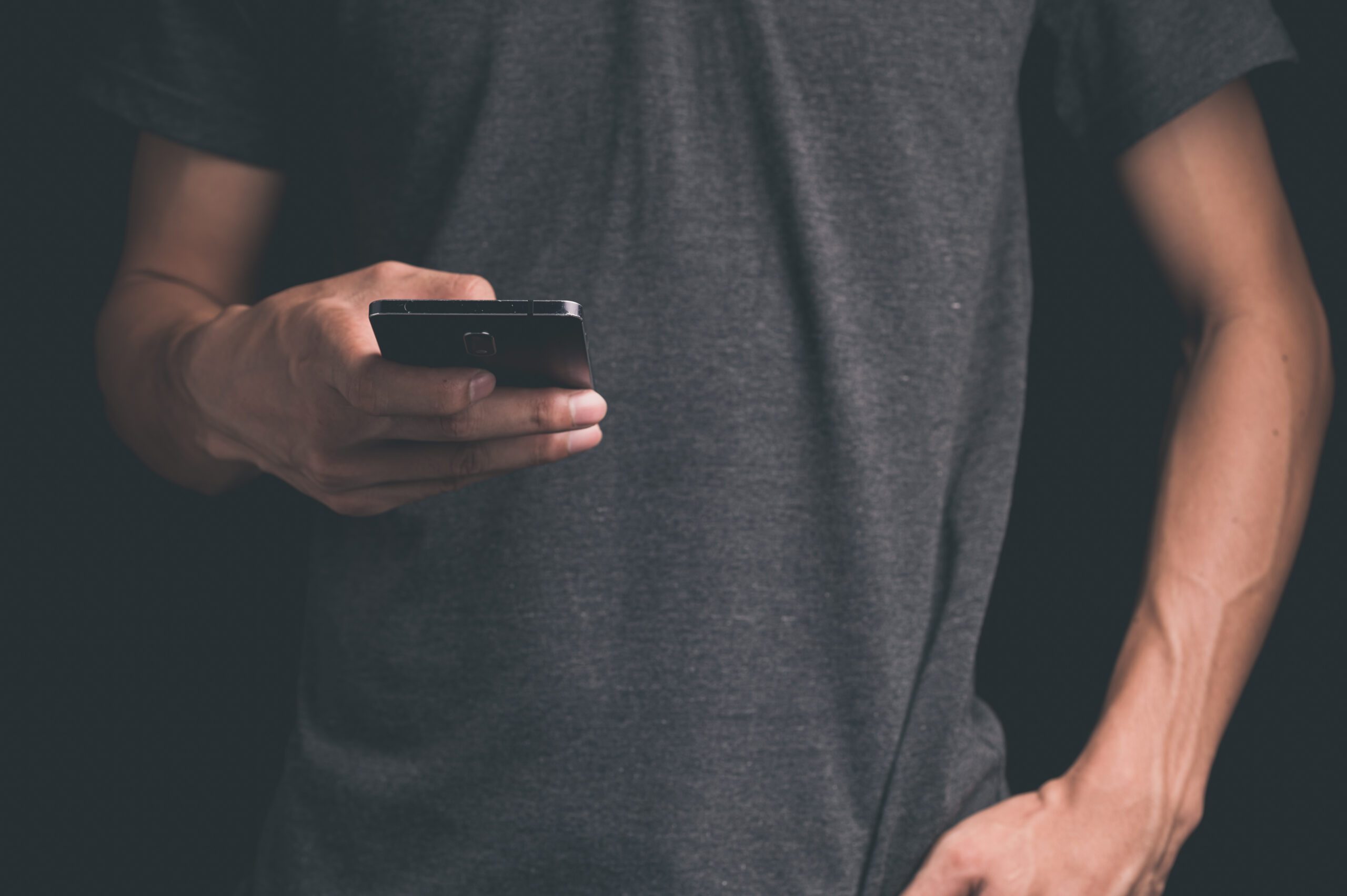 Jongere kijkt op zijn smartphone, symbool voor social media en online trends zoals mogging