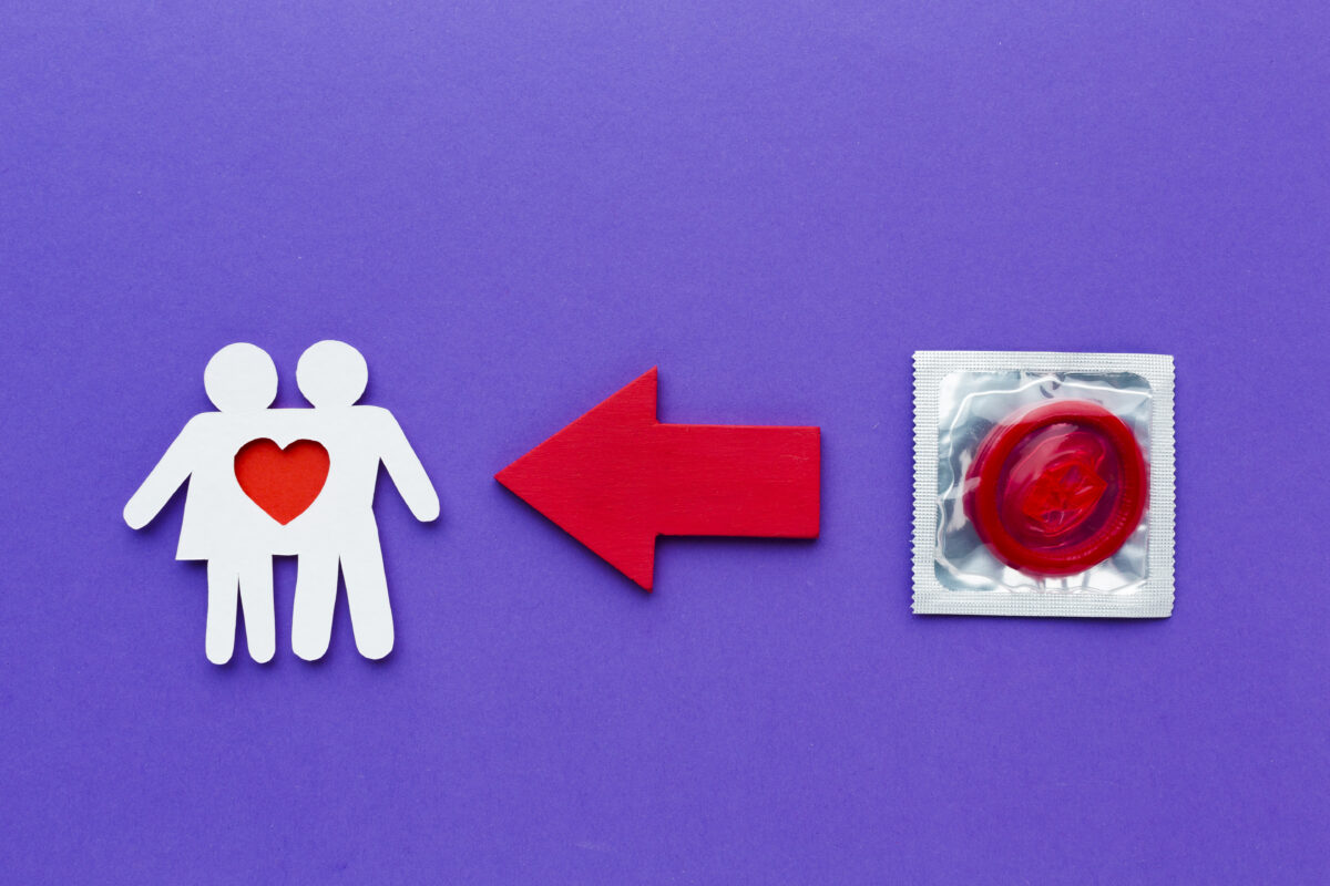 Illustratie van een rood condoom naast een papieren koppel met hartje en een rode pijl op een paarse achtergrond, als symbool voor veilige seks en soa-preventie.