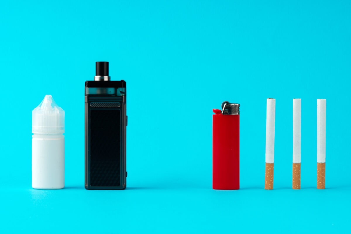 Vape en navulfles naast aansteker en drie sigaretten op een blauwe achtergrond