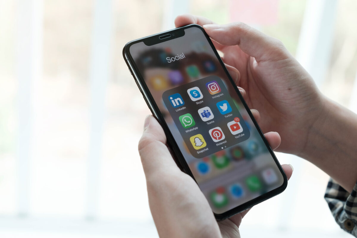 Jongere bekijkt sociale media-apps zoals Instagram, Snapchat, WhatsApp en YouTube op een smartphone.
