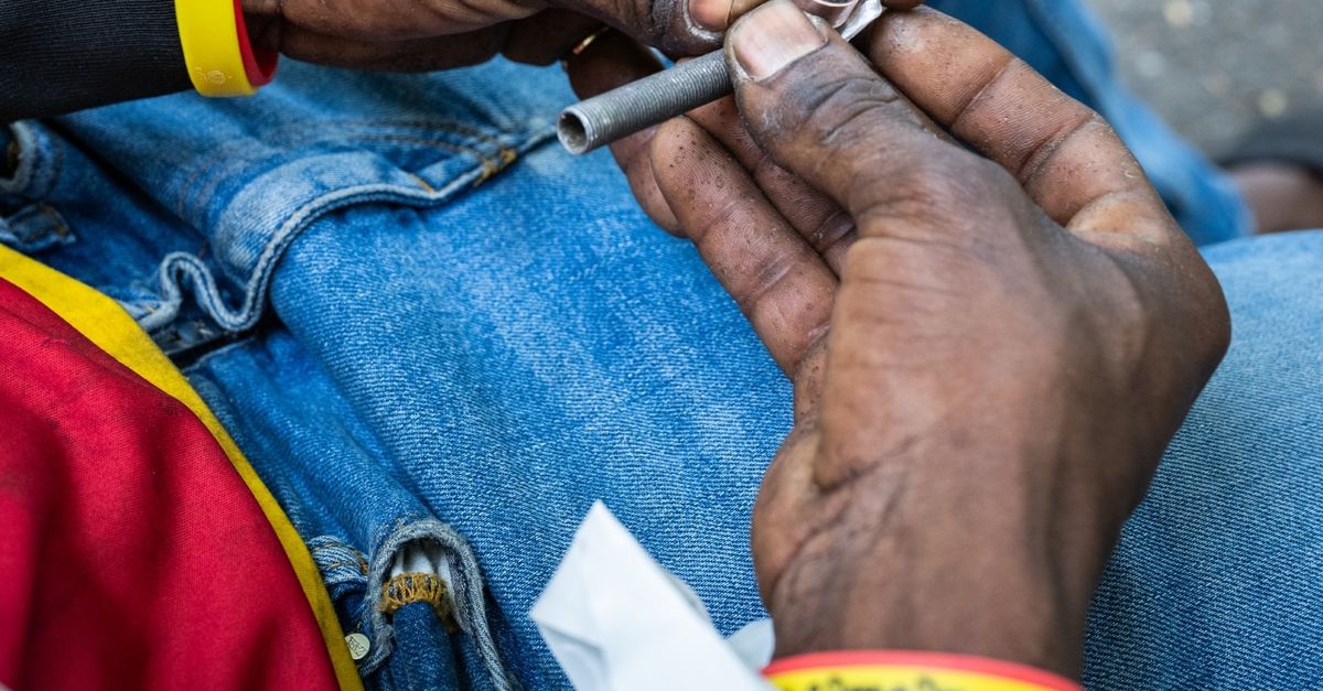 Afbeelding van NRC waarop iemand een crackpijp vasthoudt tijdens het voorbereiden van crackgebruik.