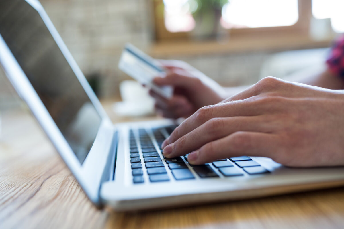 Persoon rekent online af op een laptop terwijl een betaalpas wordt vastgehouden.