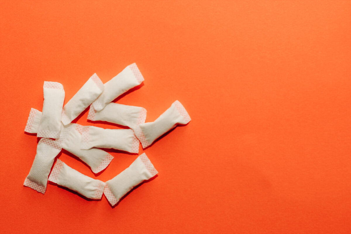 Verschillende witte caffeine pouches of energiezakjes op een oranje achtergrond.