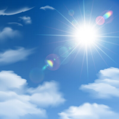 Felle zon aan een blauwe hemel met wolken, passend bij tanmaxxing en blootstelling aan UV-straling.