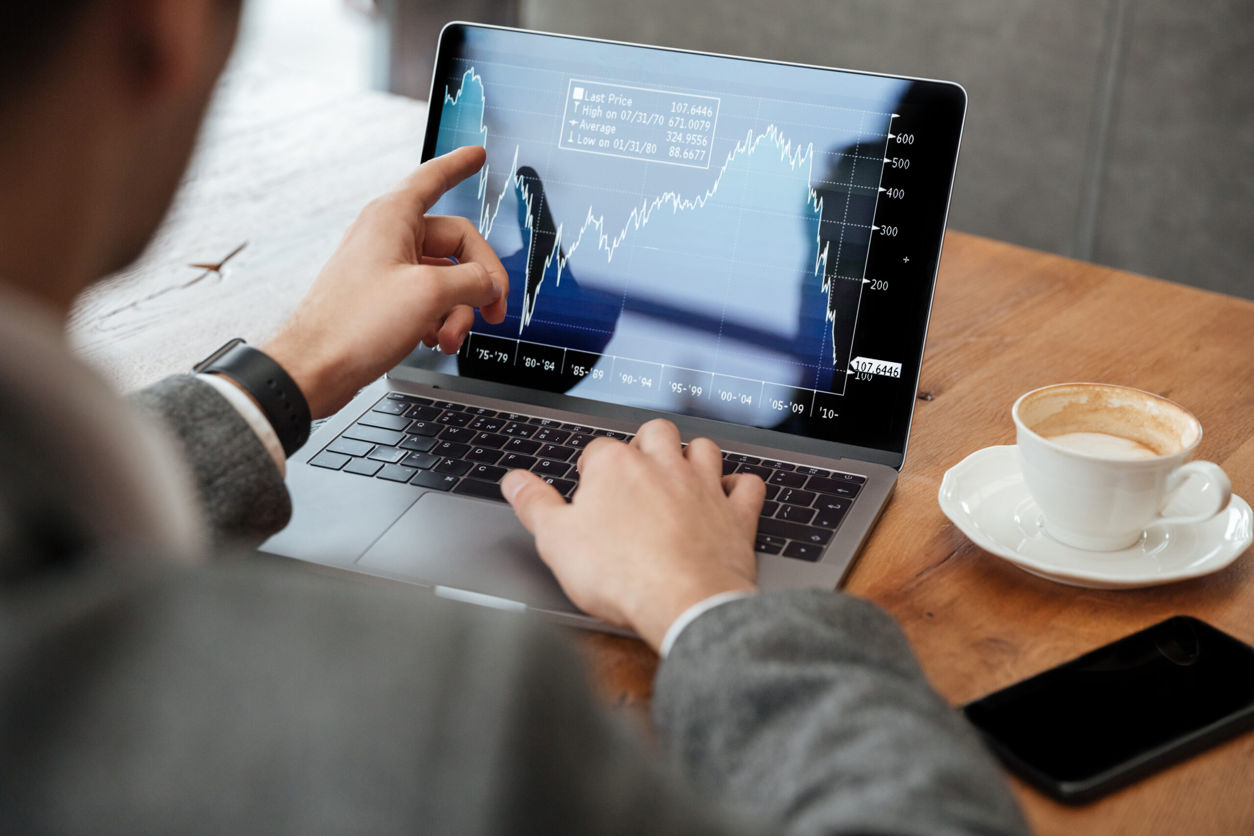 Persoon bekijkt koersgrafieken op een laptop tijdens het daytraden.
