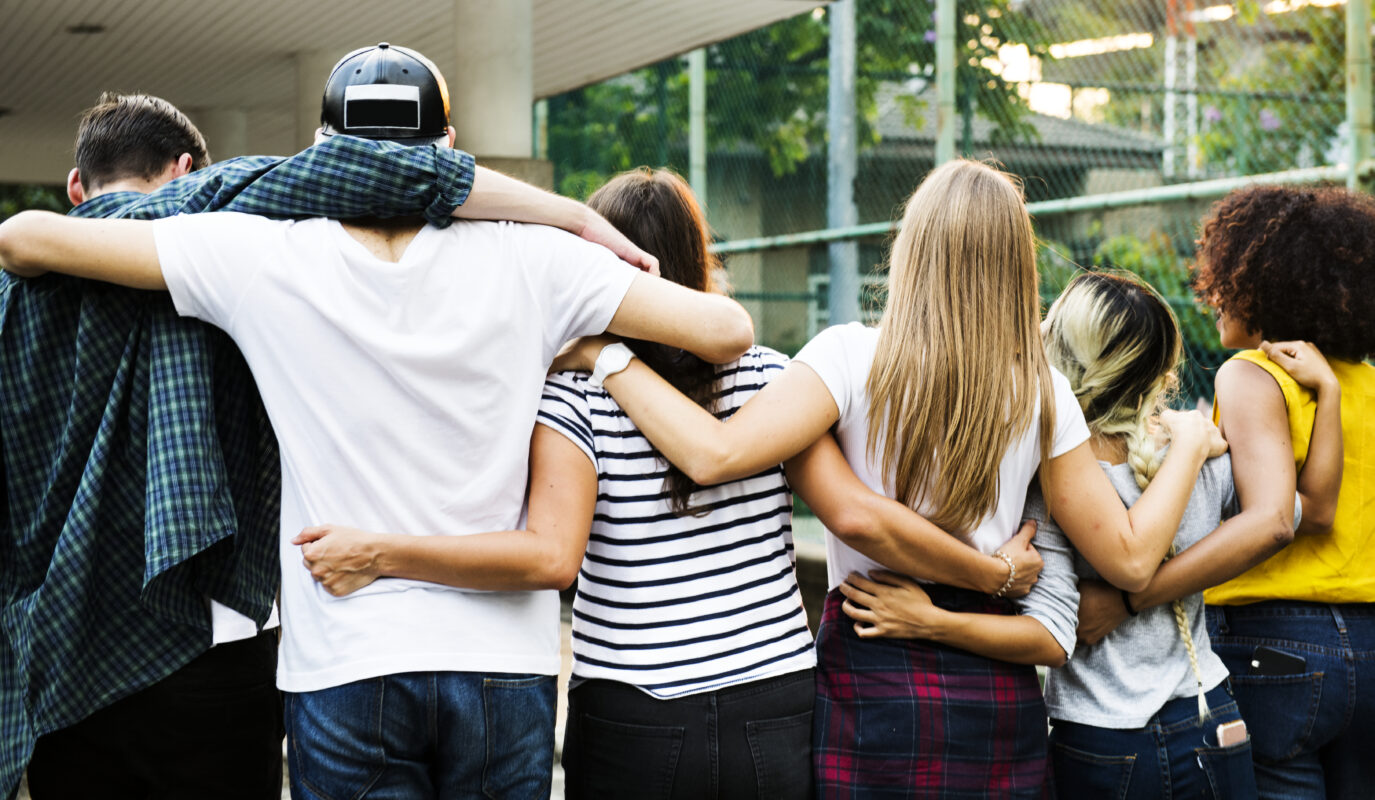 Groep jongeren staat met de armen om elkaar heen, passend bij een blog over vriendschap, erbij horen en besloten Stories op sociale media.