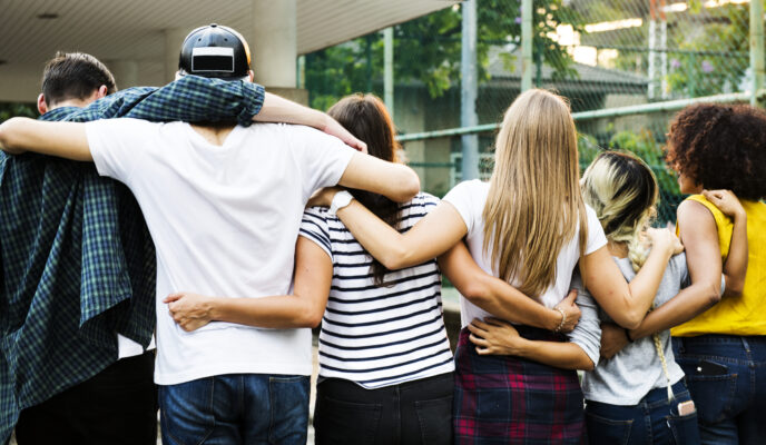 Groep jongeren staat met de armen om elkaar heen, passend bij een blog over vriendschap, erbij horen en besloten Stories op sociale media.