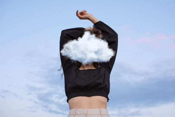 Jonge vrouw met een wolk voor haar gezicht als verbeelding van fantaseren en delulu thinking