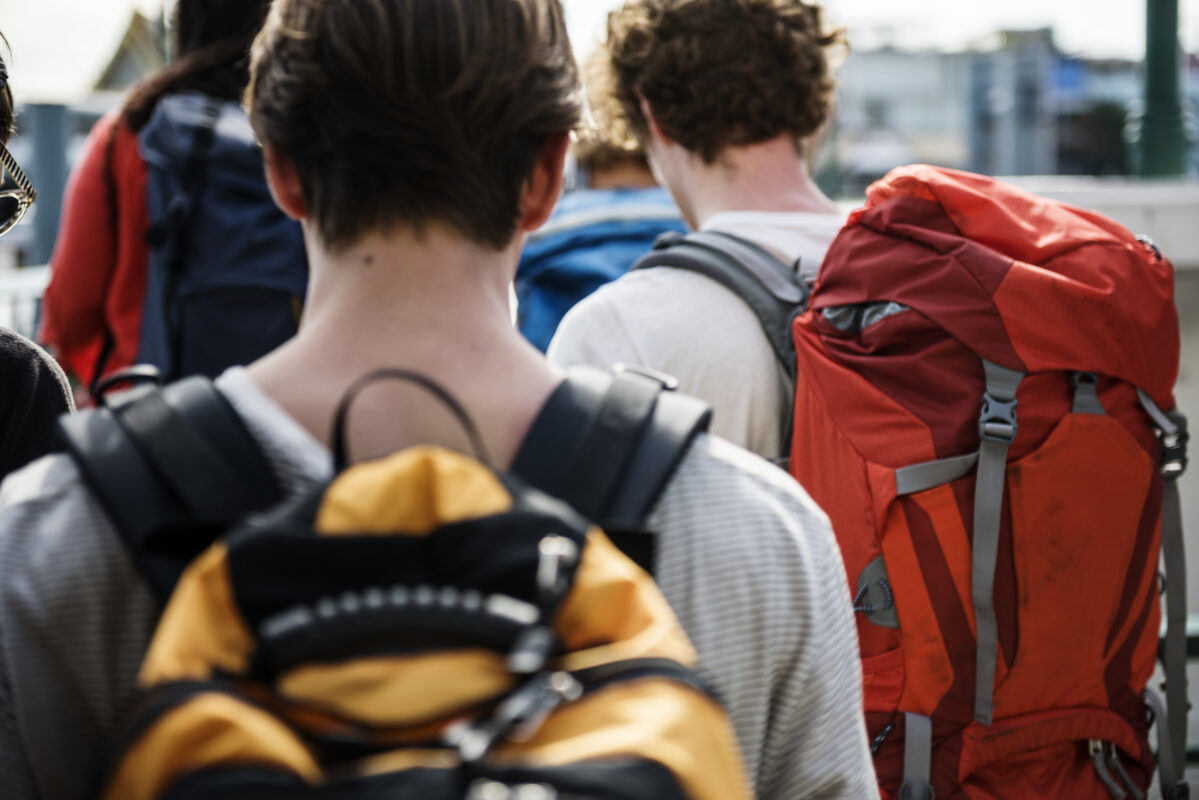 Groep jonge backpackers met grote rugzakken op reis, passend bij de micro-retirementtrend waarbij jongeren tijdelijk stoppen met werken.