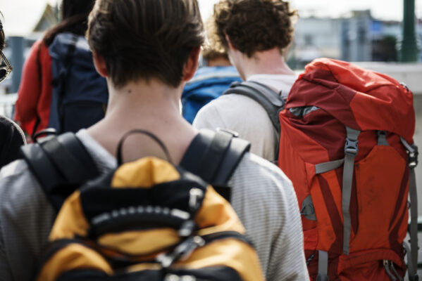 Groep jonge backpackers met grote rugzakken op reis, passend bij de micro-retirementtrend waarbij jongeren tijdelijk stoppen met werken.